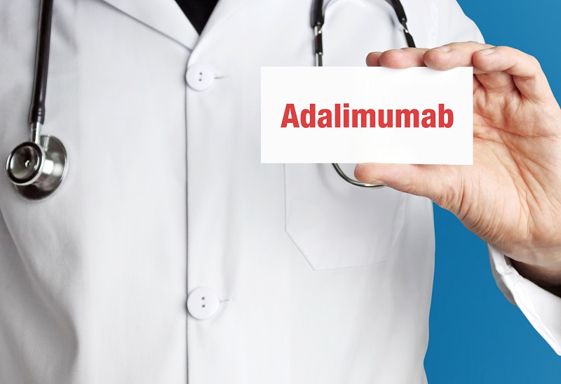 Adalimumab. Doctor in smock holds up business card. The term Ada